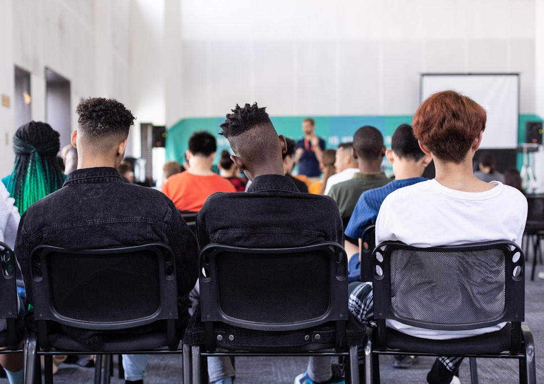 A diverse group of adult students attentively listening and engaging in a bright, modern real estate school classroom.