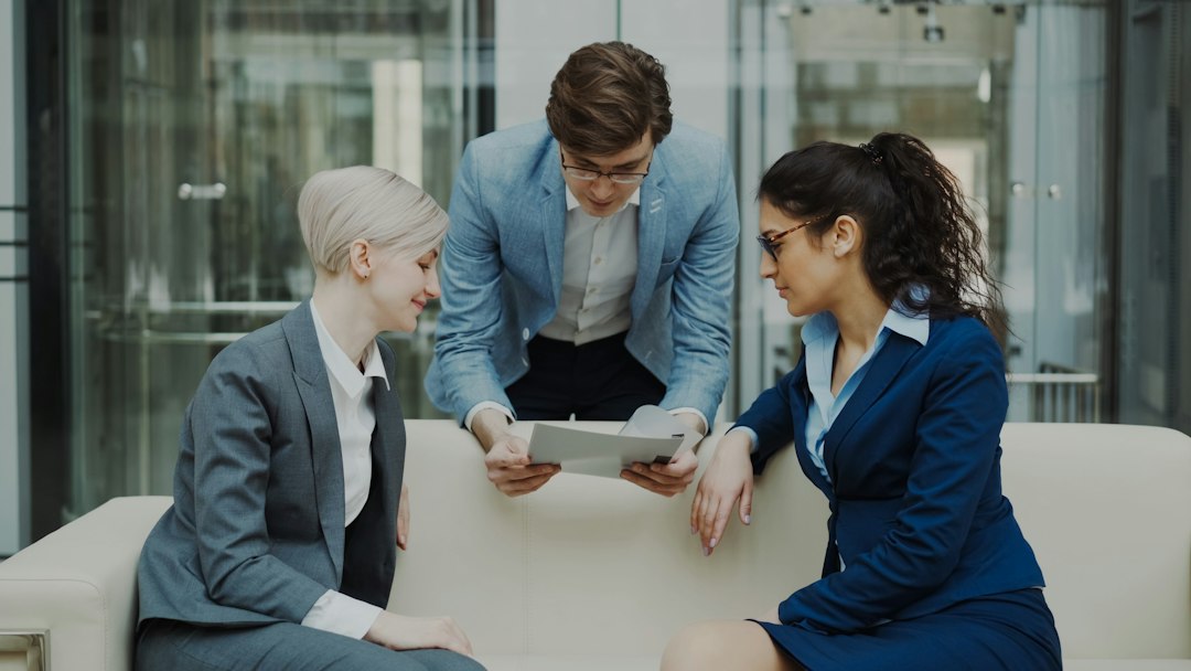 A new real estate agent shakes hands with a broker in a bright, modern office, signifying the start of their career after school.